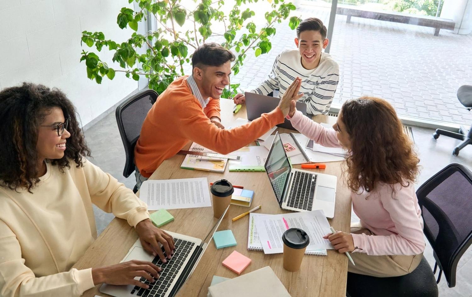 Team of colleagues collaborating and high-fiving in a well-cooled office